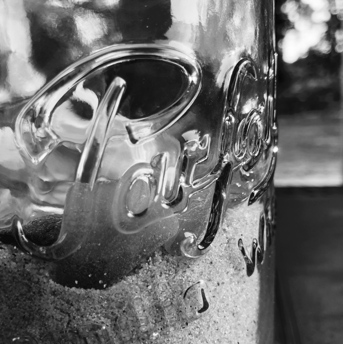 A close-up of the curved lettering and wavy glass of a traditional French preserving jar.