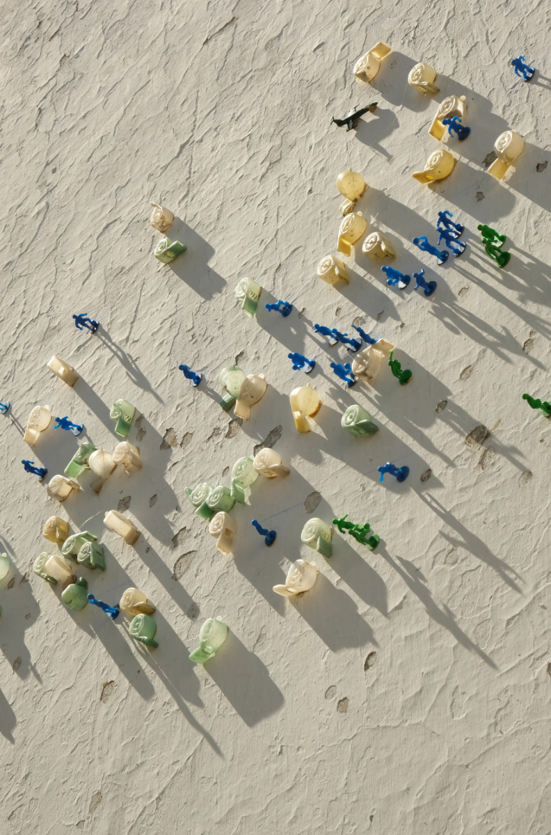 A sand-colour wall with little blue and green soldiers and plastic snails